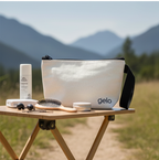 White cosmetic bag with 'gelo' branding on a wooden table outdoors with mountains in the background